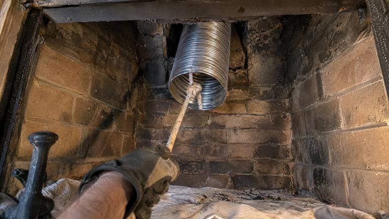 The end of a stainless steel liner comes down through the damper opening into a tan brick firebox.