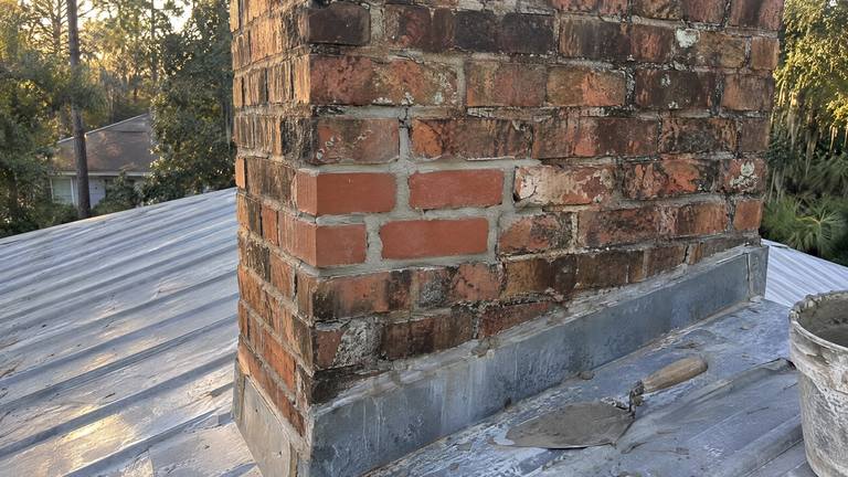 Several new bricks, slightly brighter than the old ones, are mortared into the side of an orange-red chimney.