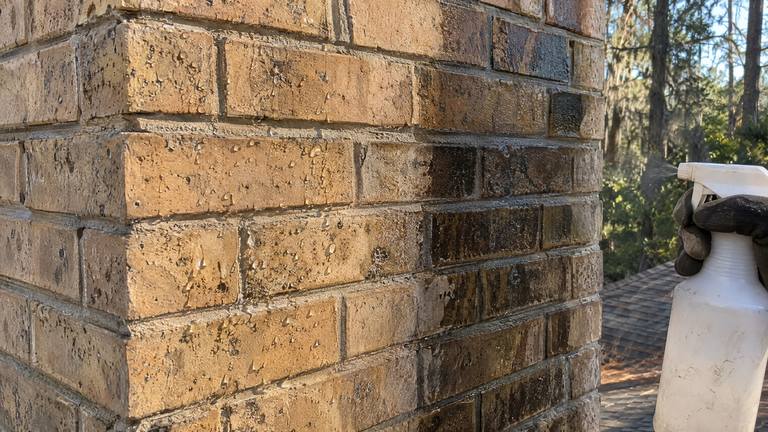 Water beads up on sealed tan brick while the unsealed brick beside it soaks the water in and darkens.